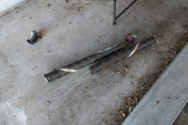 Two torsion springs removed during an emergency garage door repair in Virginia Beach, lying on the garage floor